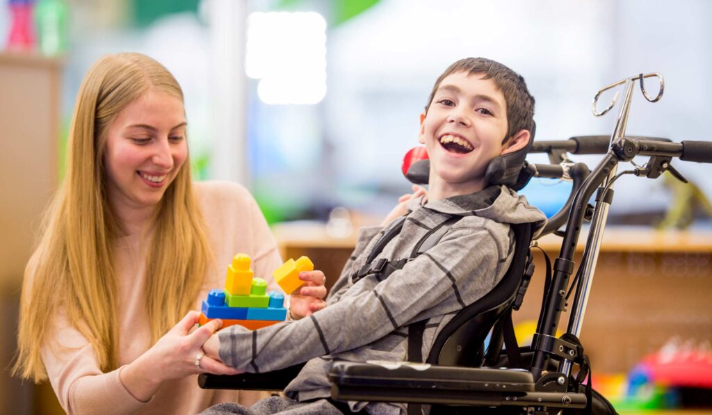 Young boy in wheel chair playing toys with therapist