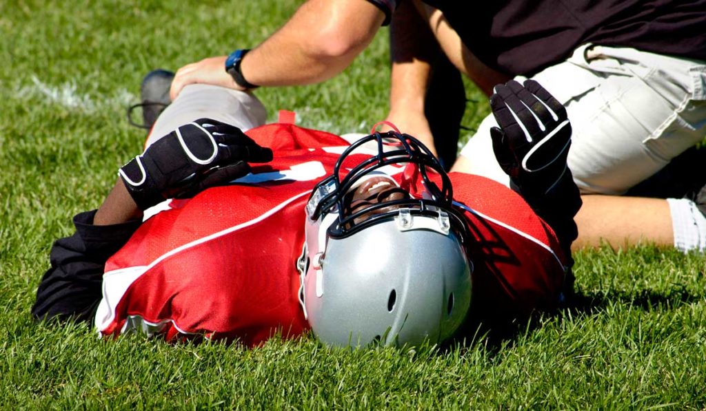 Football player lying on ground after sports-related concussion.