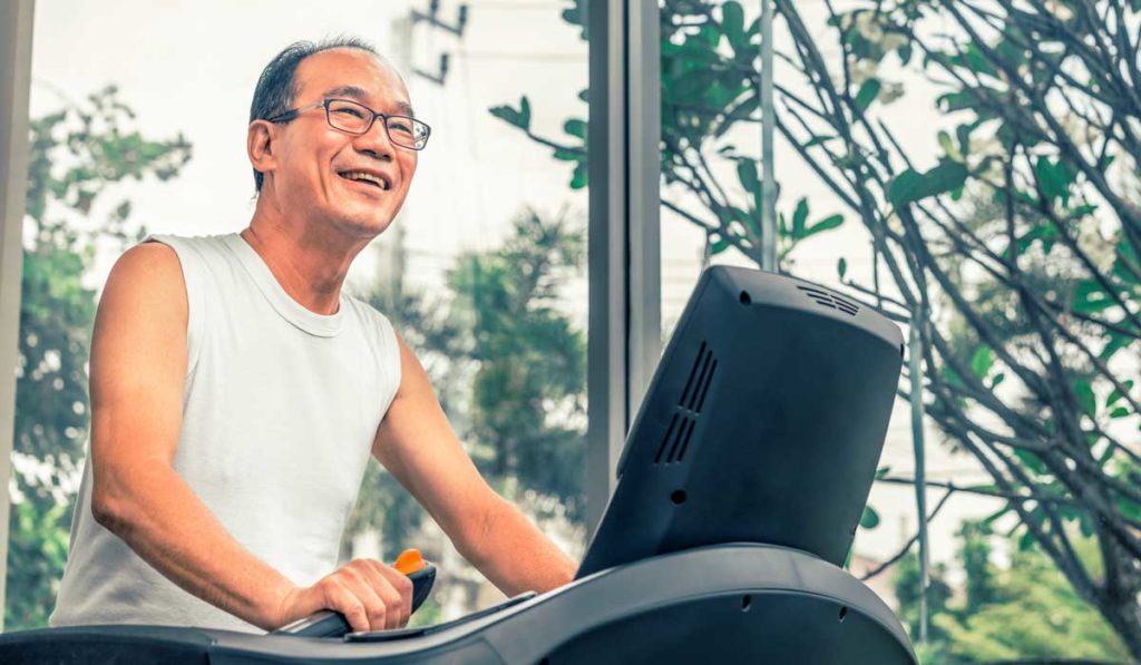 Older man exercising on treadmill as part of cardiac rehab therapy.