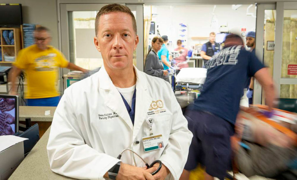 A doctor in a busy emergency department room.