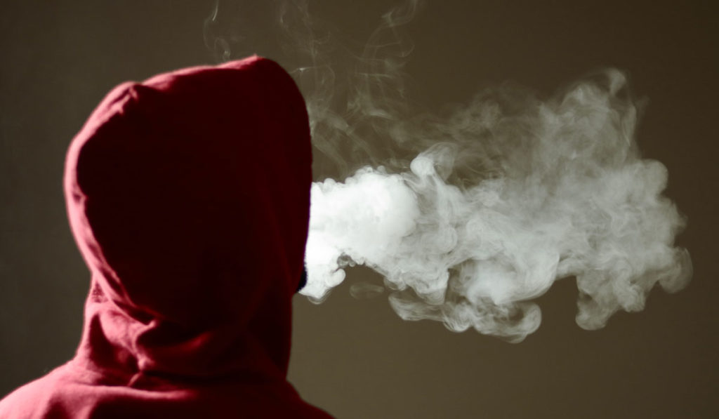 Teen blowing smoke from an e-cigarette.