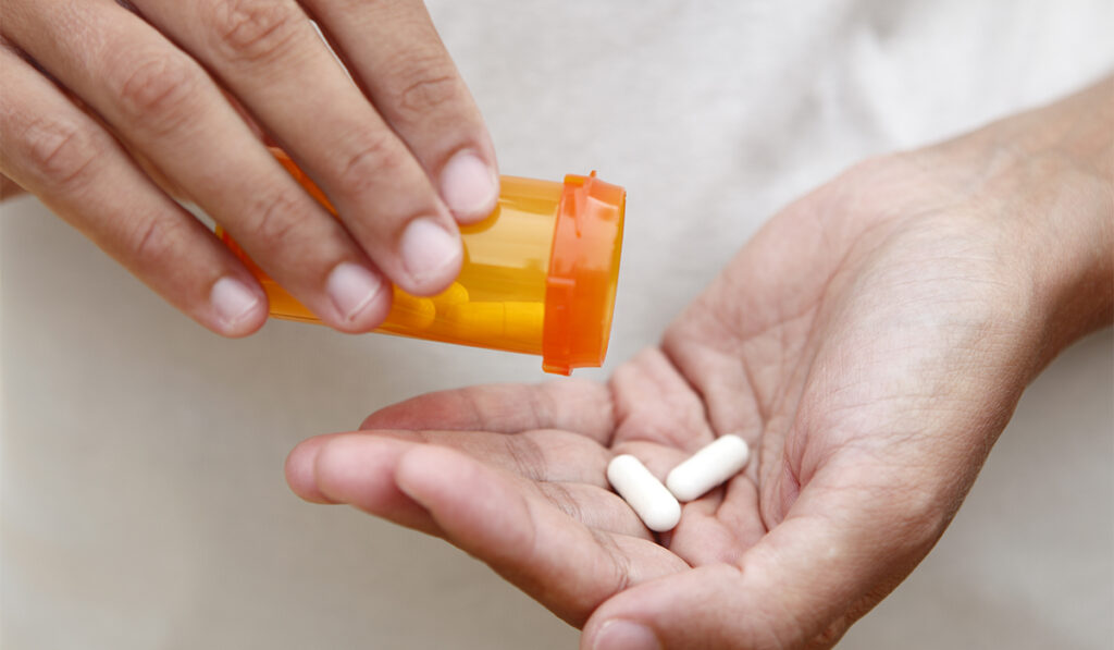Prescription bottle pouring pills into hand
