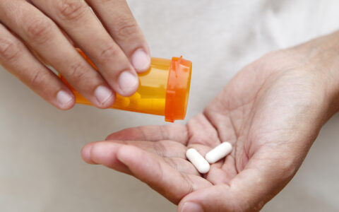 Prescription bottle pouring pills into hand