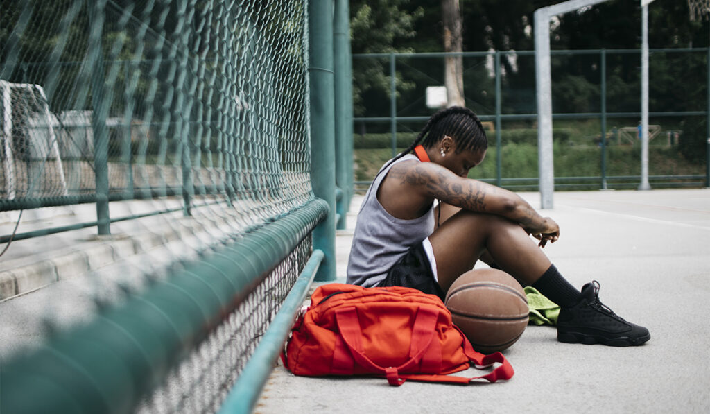 Athlete resting on the ground of a basketball court.