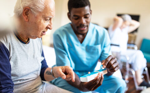 Nurse helping older man with medication