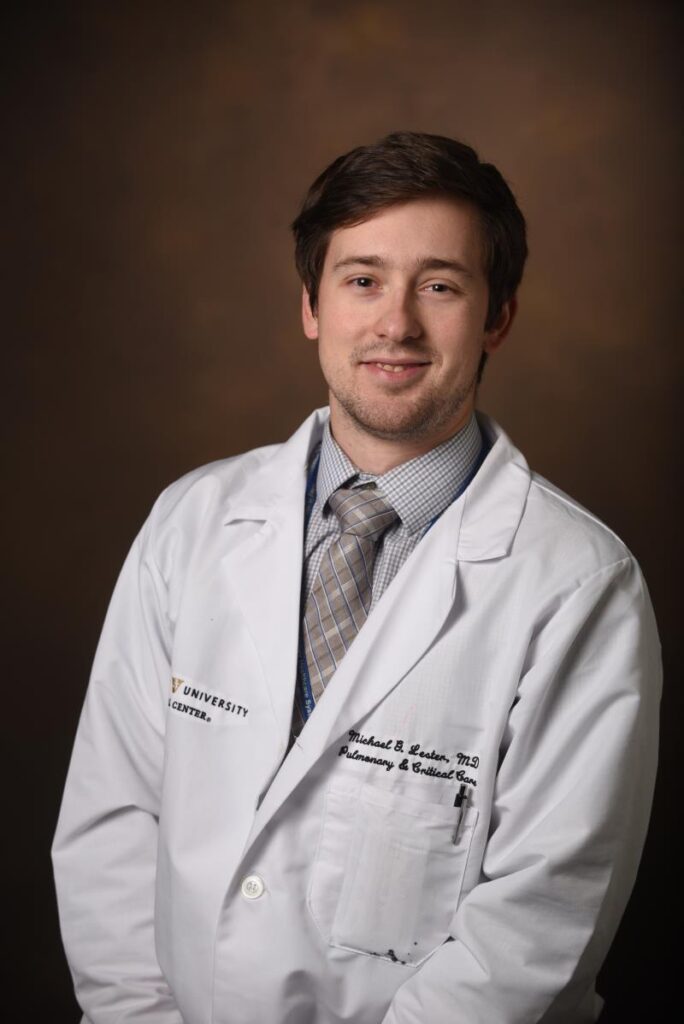 Portrait of Dr. Michael G. Lester, a white male with dark hair in a white coat and gray shirt, with a tie