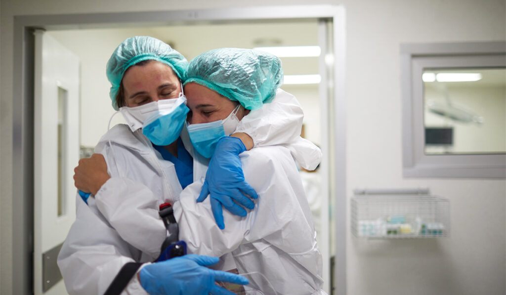 Nurses hugging while wearing protective gear