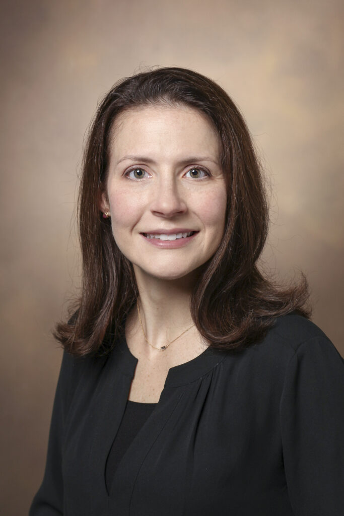 Portrait of Dr. Anna E. Patrick, a white woman with brown hair in a black shirt