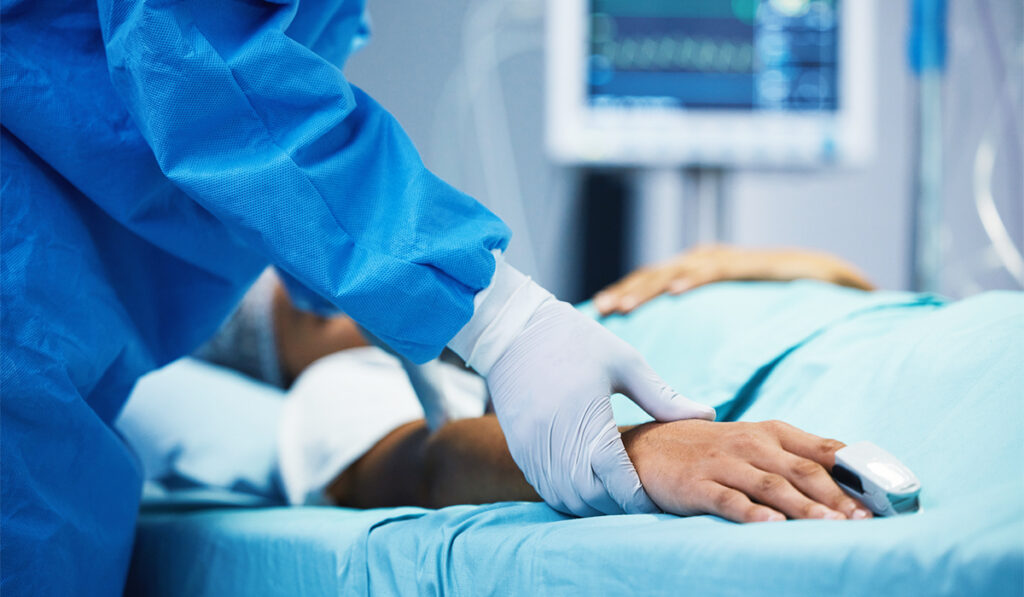 Doctor holding patient's hand in critical care unit