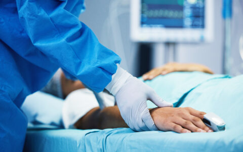 Doctor holding patient's hand in critical care unit