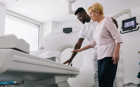 Male staff guides an elderly woman to an MRI machine