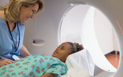 Nurse reassures girl lying down in an MRI machiine