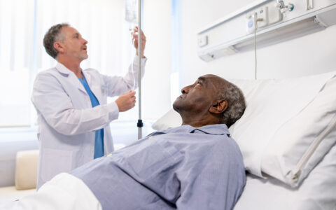 Doctor adjusting the IV drip on a hospitalized senior patient