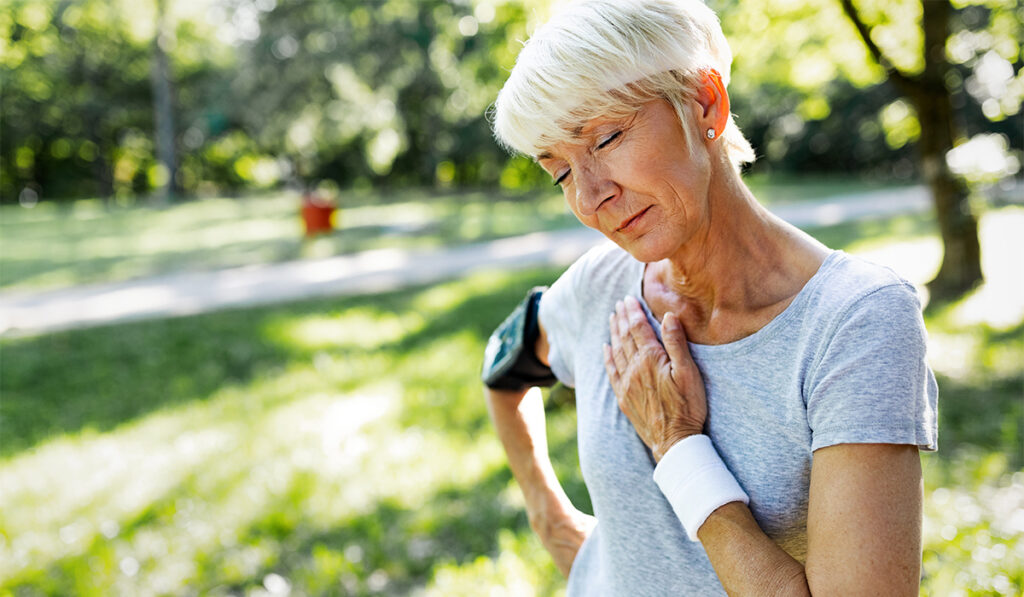 Senior woman with chest pain suffering from heart attack during jogging