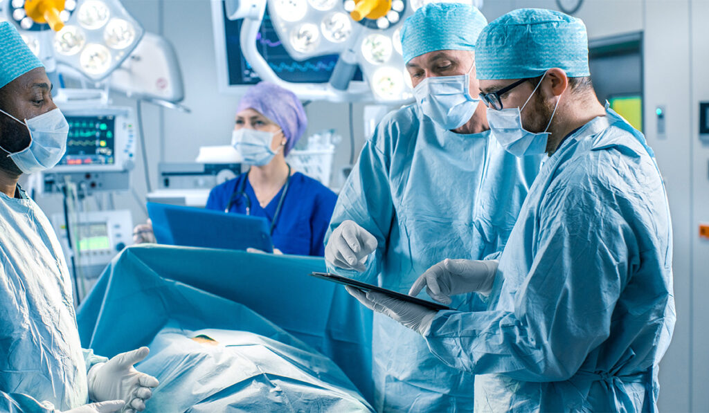 professional surgeons and assistants talk and use digital tablet computer during surgery