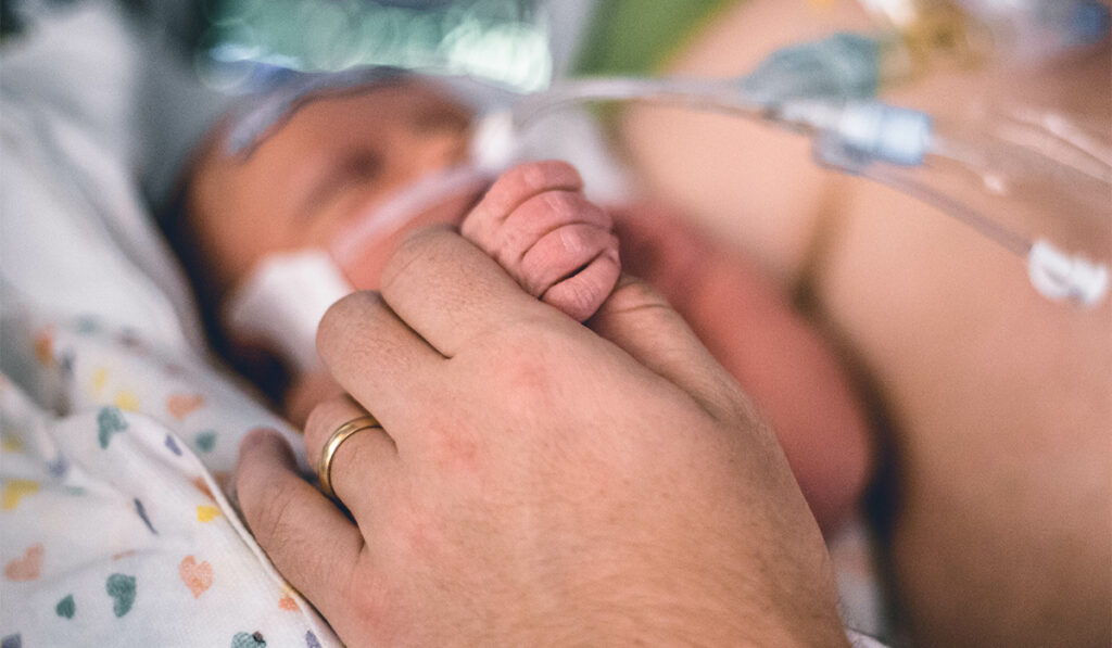 Closeup of adult holding infant's hand