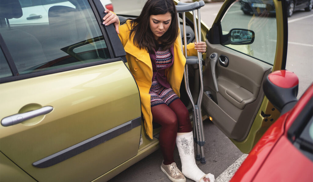 Woman with crutches getting out of the passenger side of a car