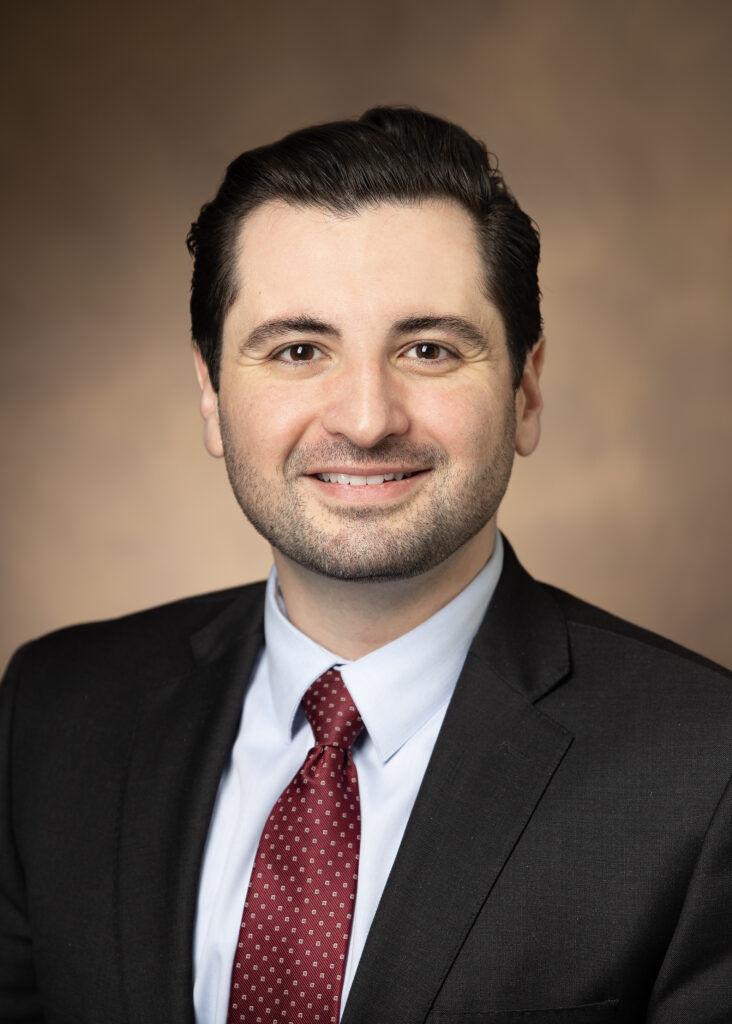 Photo of man with black hair, black suit and tie