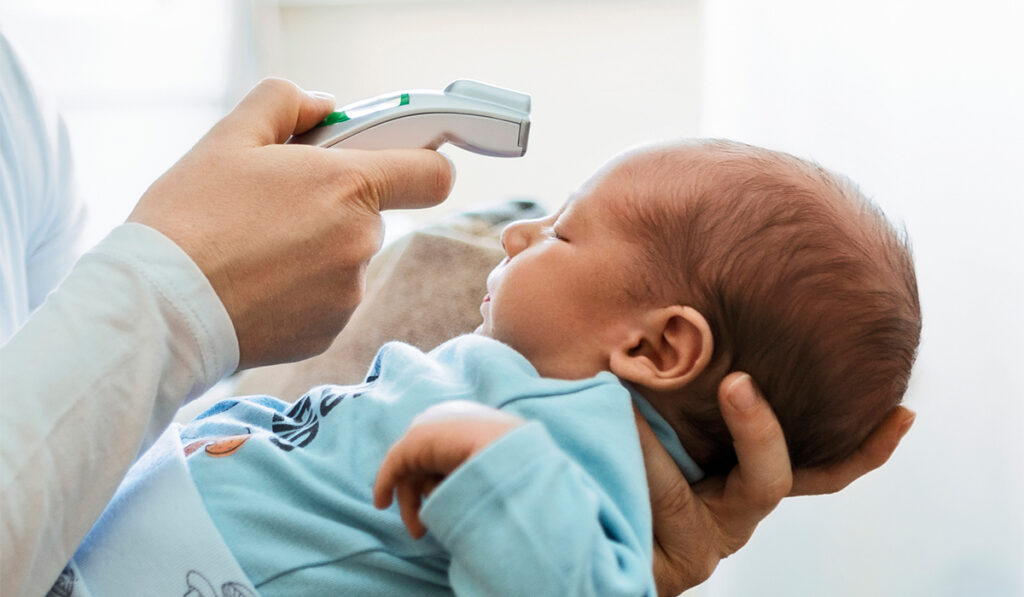 Taking a baby's temperature with a digital forehead thermometer