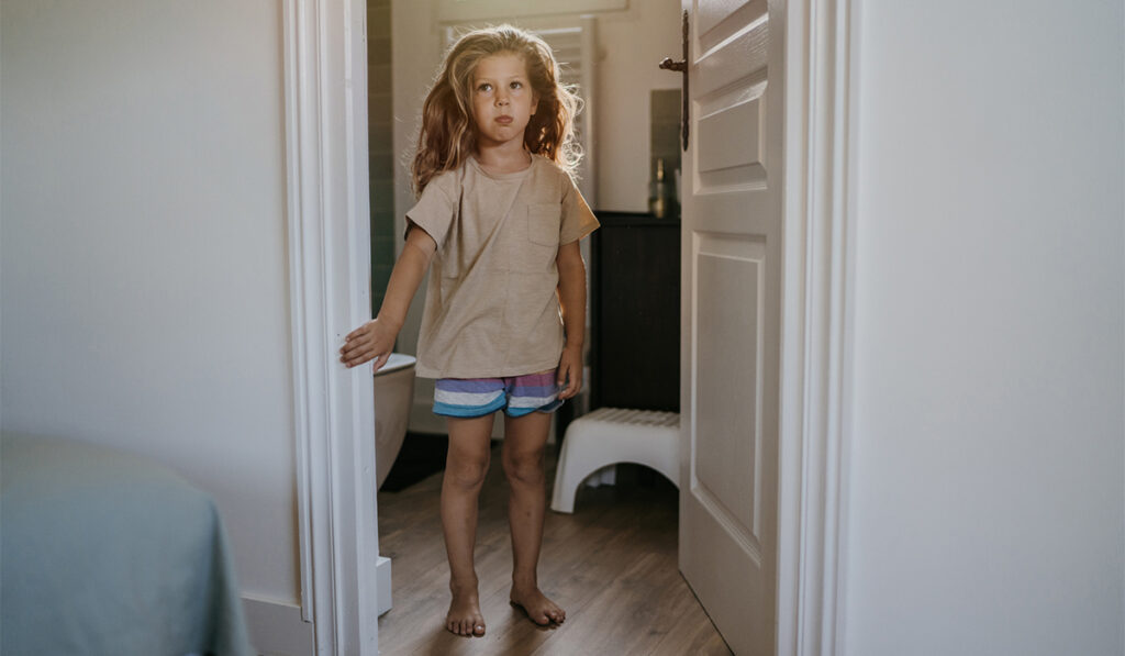 Little girl standing inside a bathroom