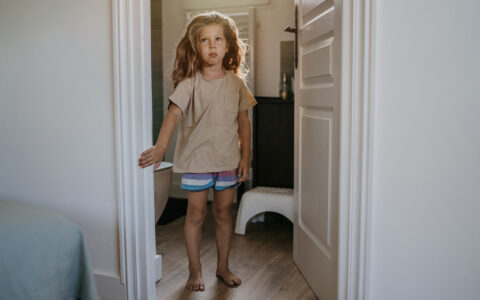 Little girl standing inside a bathroom